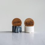 Marble salt and pepper cellars with wooden lids engraved “salt” and “pepper.”