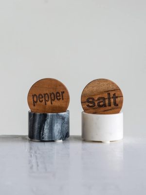 Marble salt and pepper cellars with wooden lids engraved “salt” and “pepper.”