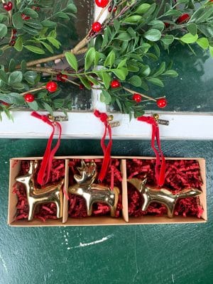 Gift box with moose, deer, and fox gold ornaments nestled in red filler