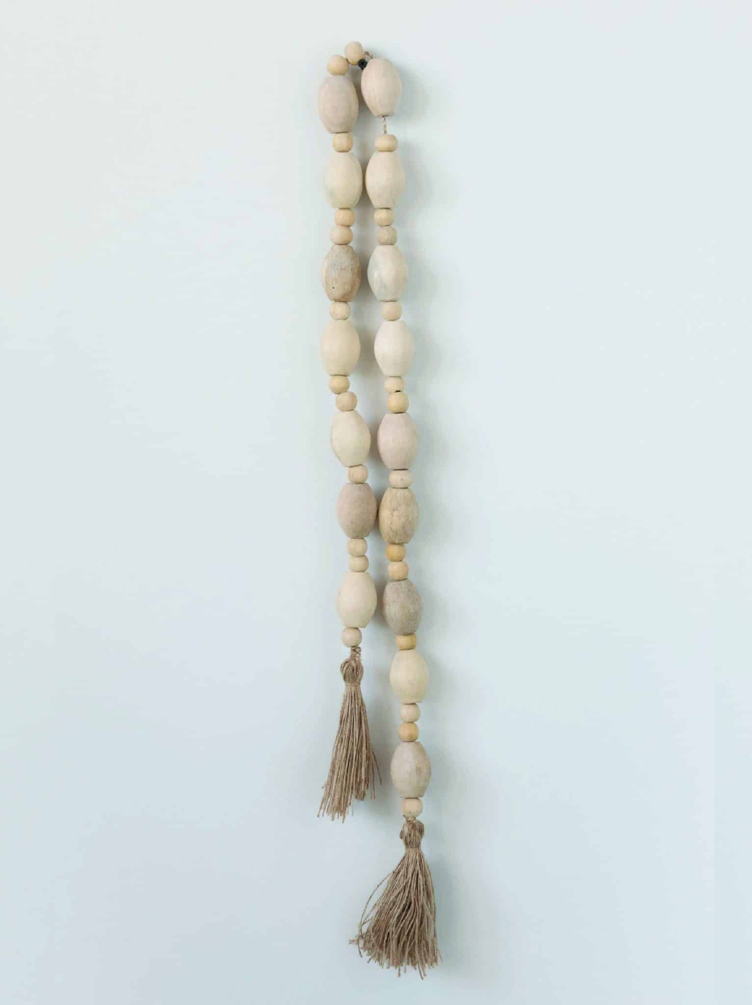 Natural mango wood beaded garland with jute tassels hanging vertically.