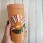Inspirational “Be You” sticker on an orange tumbler, showing retro sunrise design and motivational words.
