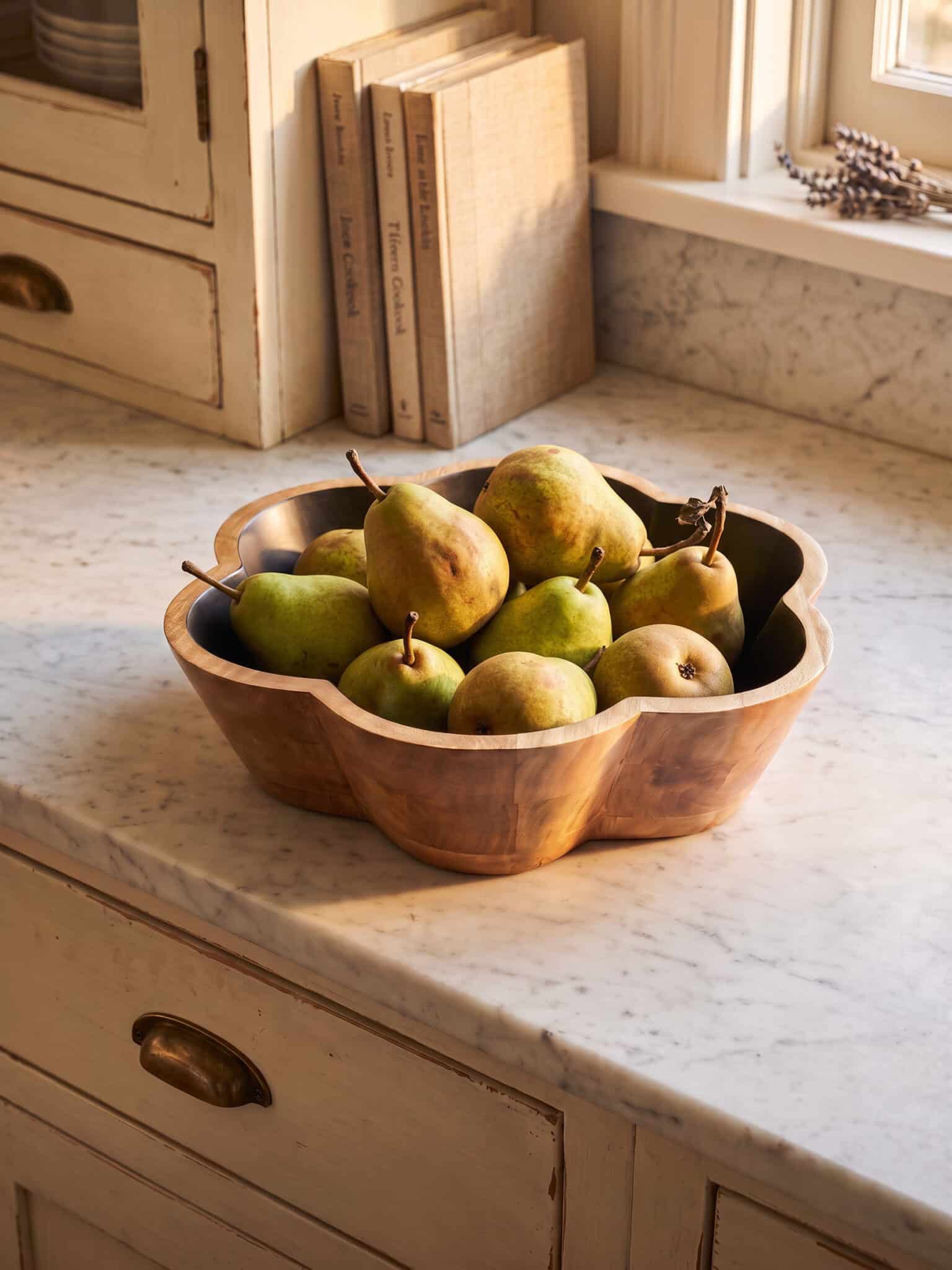 The black scalloped mango wood bowl holding fruit on kitchen countertop.