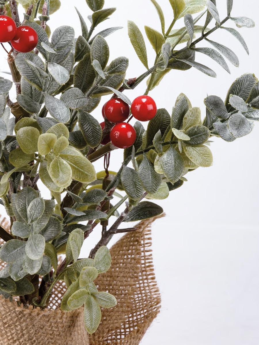 Close-up of faux red berries and eucalyptus leaves on a small holiday tree
