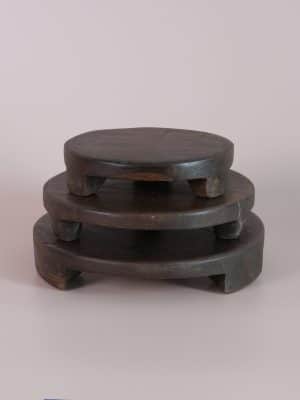 Stack of three Found Wood Pedestals in small, medium, and large sizes, each with a dark, rustic finish and hand-carved feet.