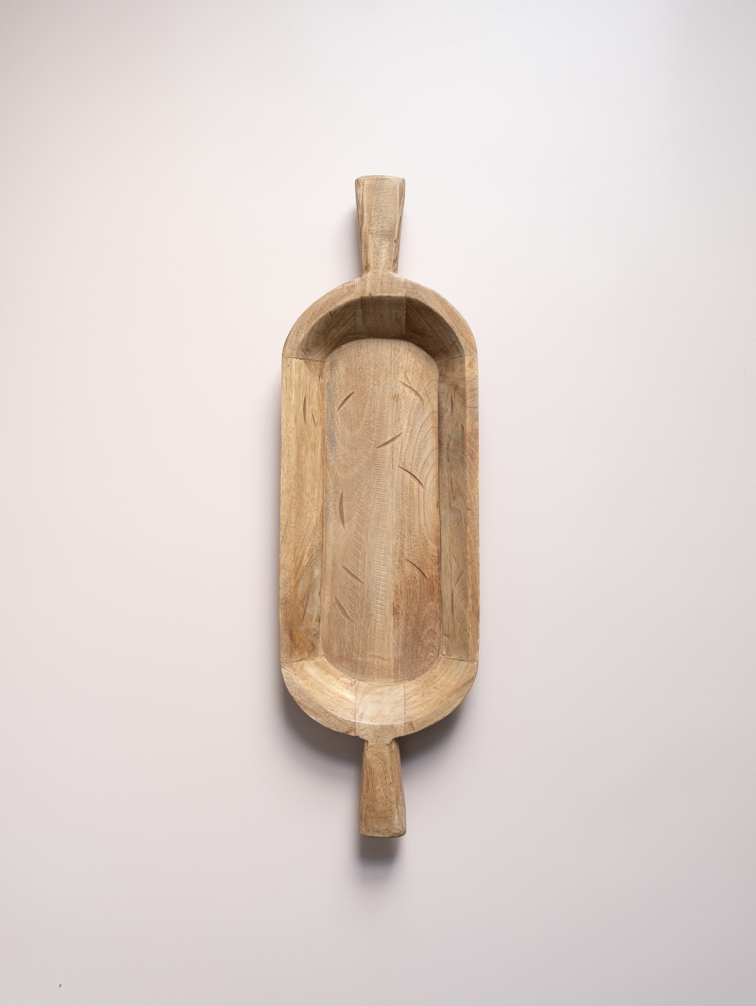 Hand-carved wood dough bowl with large side handles, featuring a natural grain pattern and long, narrow shape.