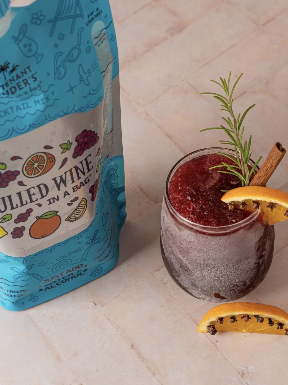 Mulled Wine cocktail pouch with a glass of red spiced drink garnished with orange slice, rosemary, and cinnamon stick.