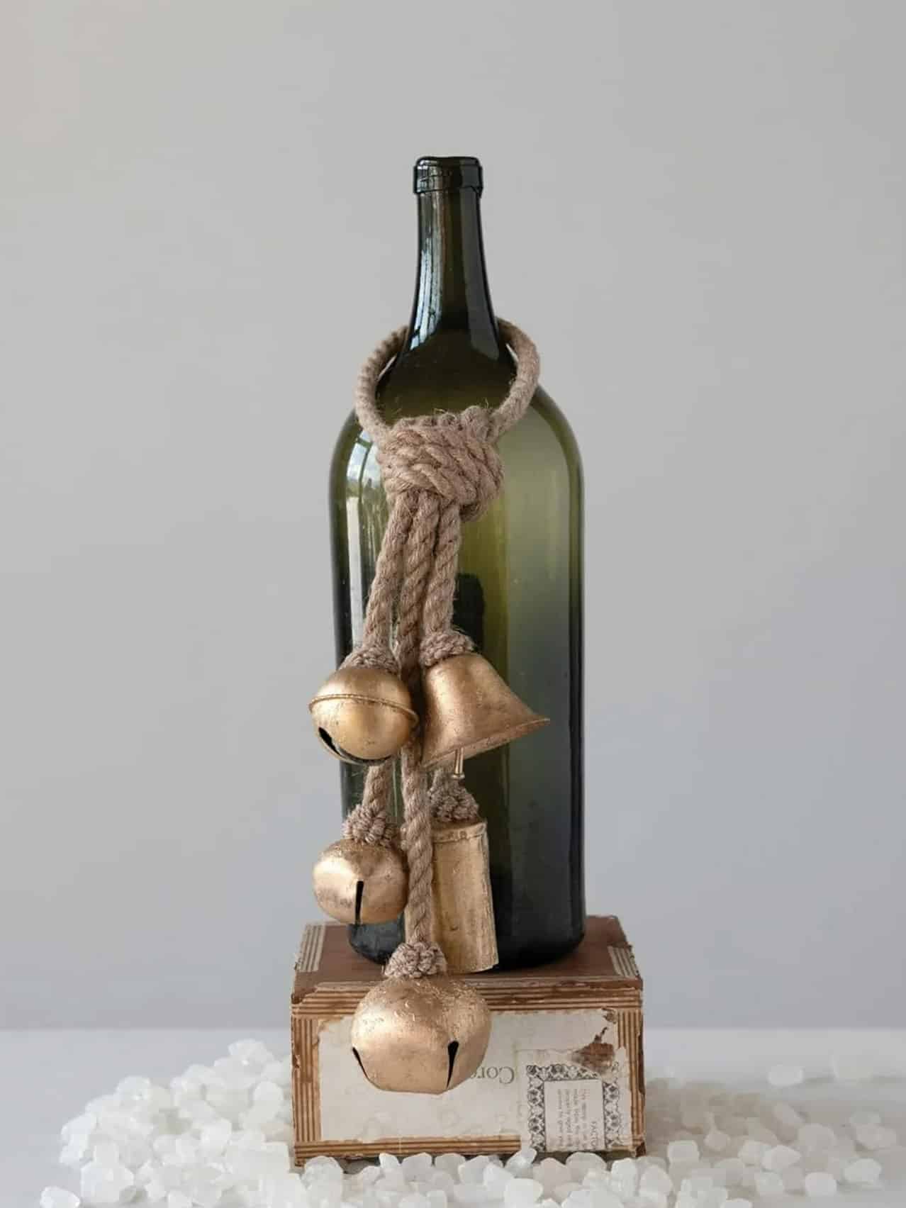 be-made-hays-ks-hanging-gold-bells-with-jute-rope Set of Hanging Gold Bells with natural jute rope displayed over a green glass bottle for a simple, rustic holiday accent.