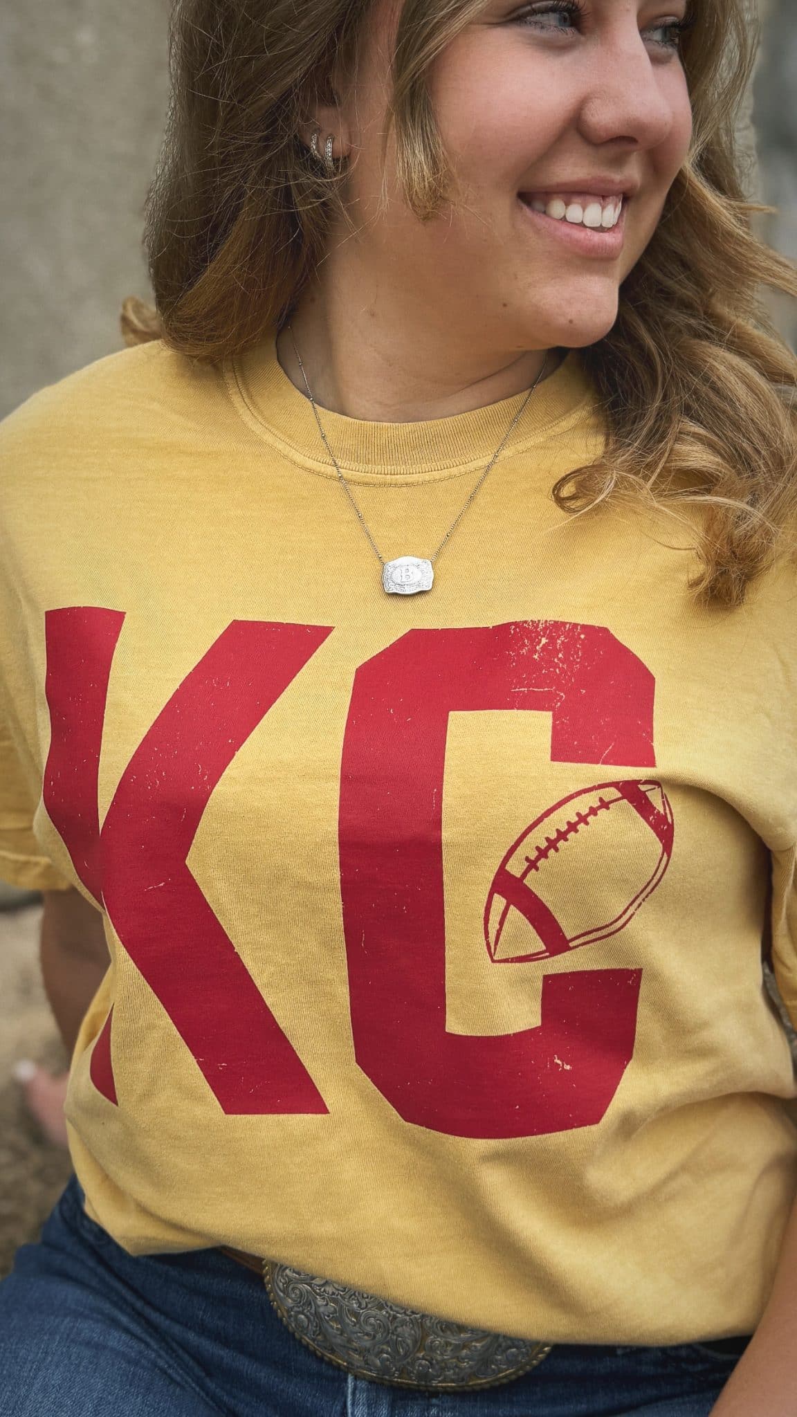 Close-up of distressed red KC football design on mustard Comfort Colors Vintage KC Football Graphic Tee.