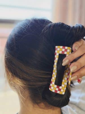 Close-up of red, gold, and white checkered acrylic claw clip securing a twisted hairstyle.