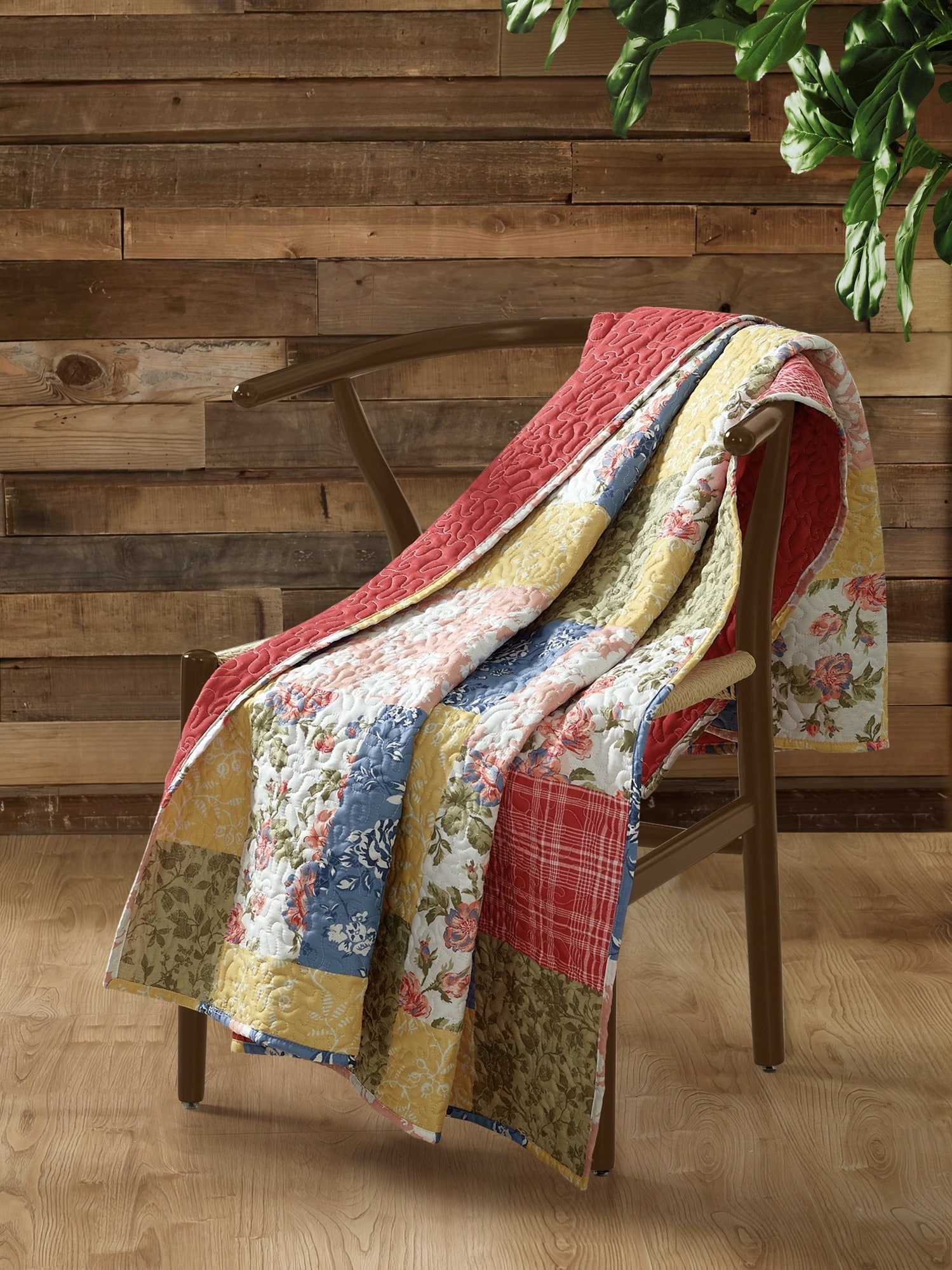 Floral Quilt Farmhouse Throw Blanket draped over a wooden chair in a rustic setting