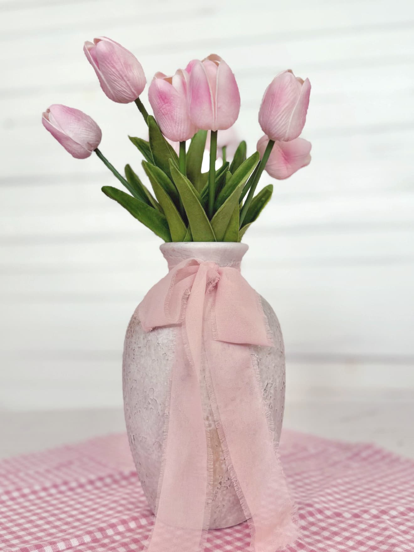 Light Pink Tulip Bundle arranged in a Medium Rustic White Vase tied with a rose chiffon ribbon, styled on a pink gingham square table runner.