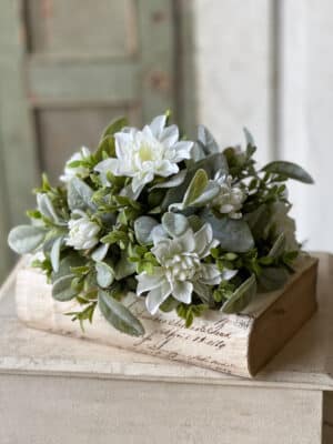 White Cottage Blooms Half Sphere styled on a decorative book with layered greenery and white blooms