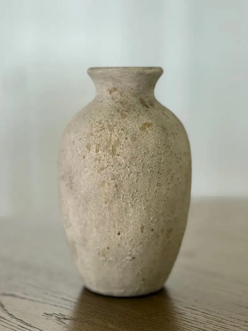 Medium rustic white vase with a curved silhouette and weathered, textured finish on a neutral surface.