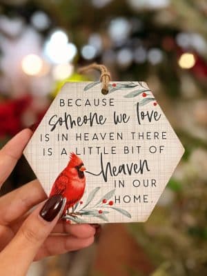 Close-up of the “Someone We Love Is in Heaven” cardinal ornament held in hand, showing the hexagon shape and red cardinal artwork.