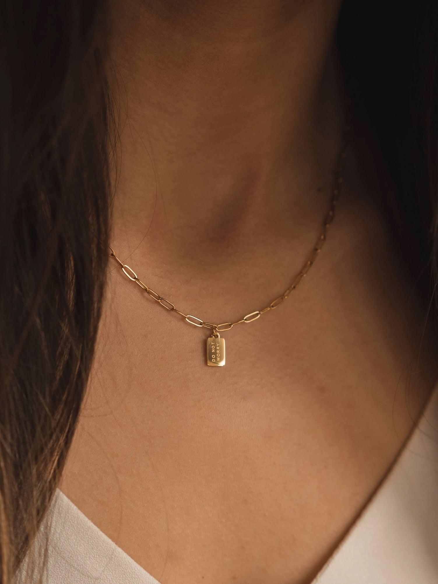 Woman wearing Do Not Worry Mini Tag Necklace on gold paperclip chain