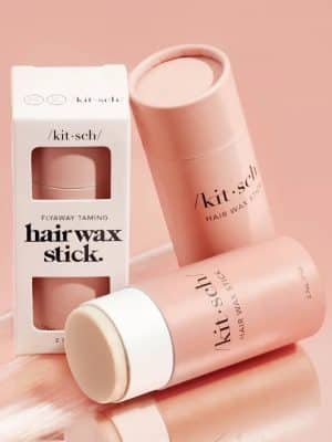 Pink biodegradable Kitsch Hair Wax Stick with packaging displayed on a blush background.