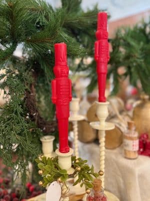 Red nutcracker taper candles styled in off-white corkscrew candle holders with greenery accents and holiday décor.