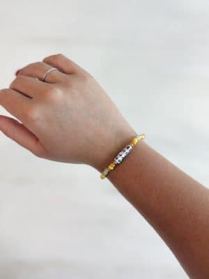 Single-strand bracelet with yellow beads and the word GLOW in block letters, styled on wrist.
