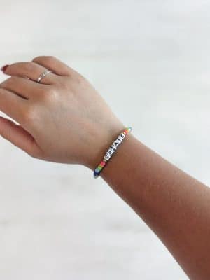Colorful beaded bracelet spelling CREATE in block letters, worn on wrist.