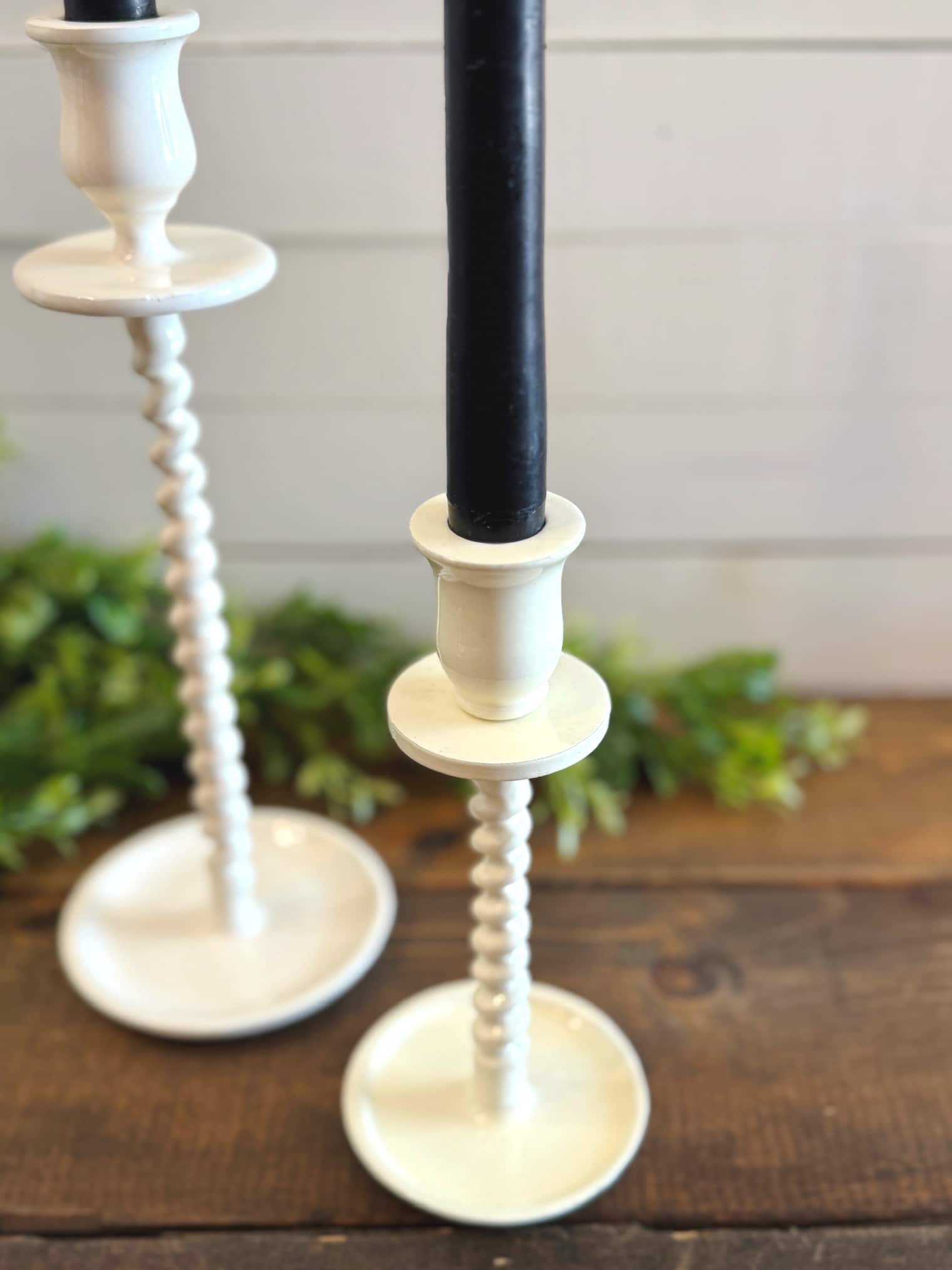 Pair of off-white corkscrew taper candle holders with black taper candles on a wood surface