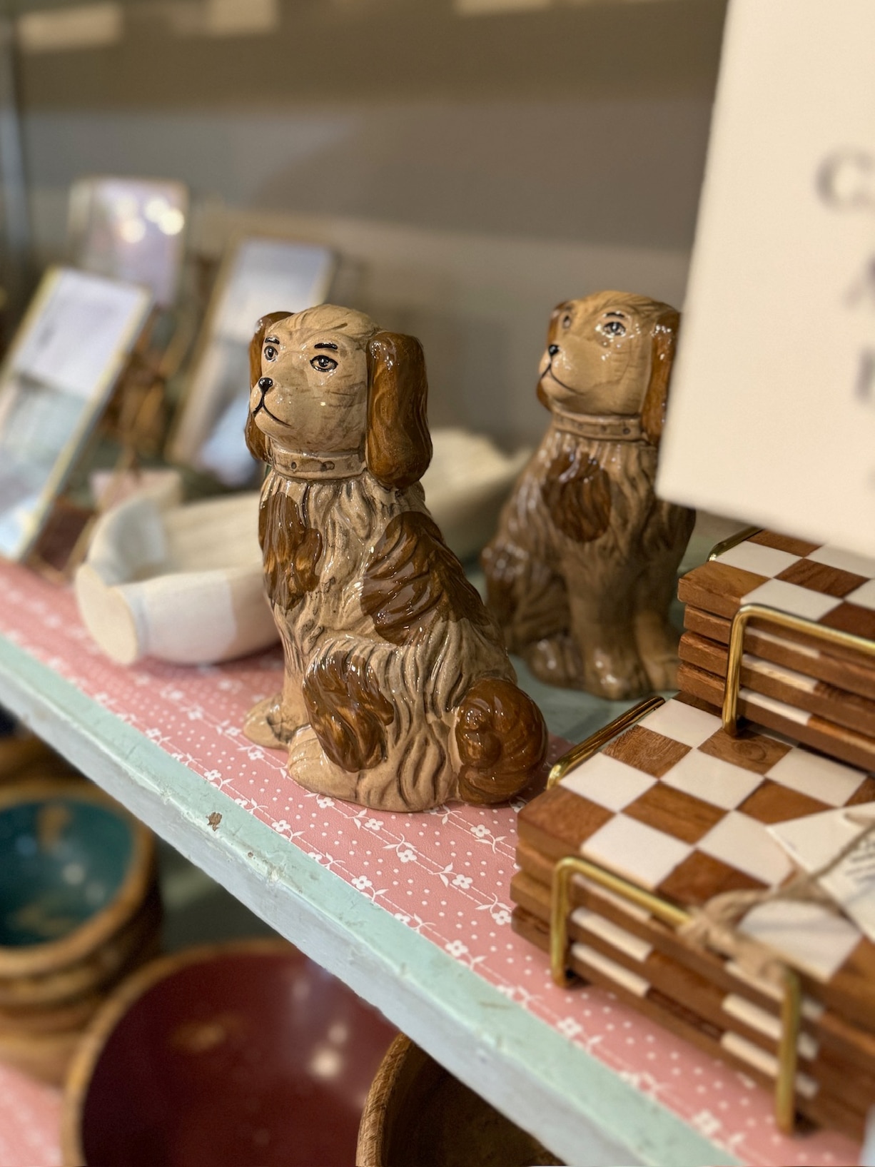 Two Staffordshire-style dog planters in brown tones displayed on a decorative shelf beside vintage-inspired accessories.