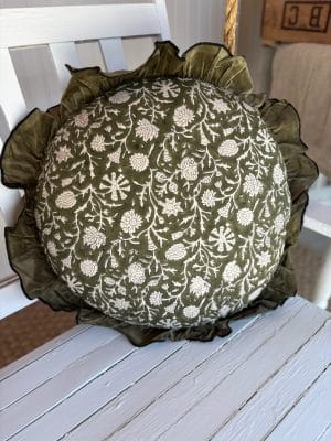 Green Block Print Floral Round Pillow with white floral vine pattern and ruffle edge resting on a white chair.