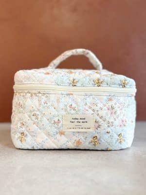 Front-facing view of the large quilted makeup bag with top zipper and stitched label that reads “Take the Time. Enjoy the Now.”