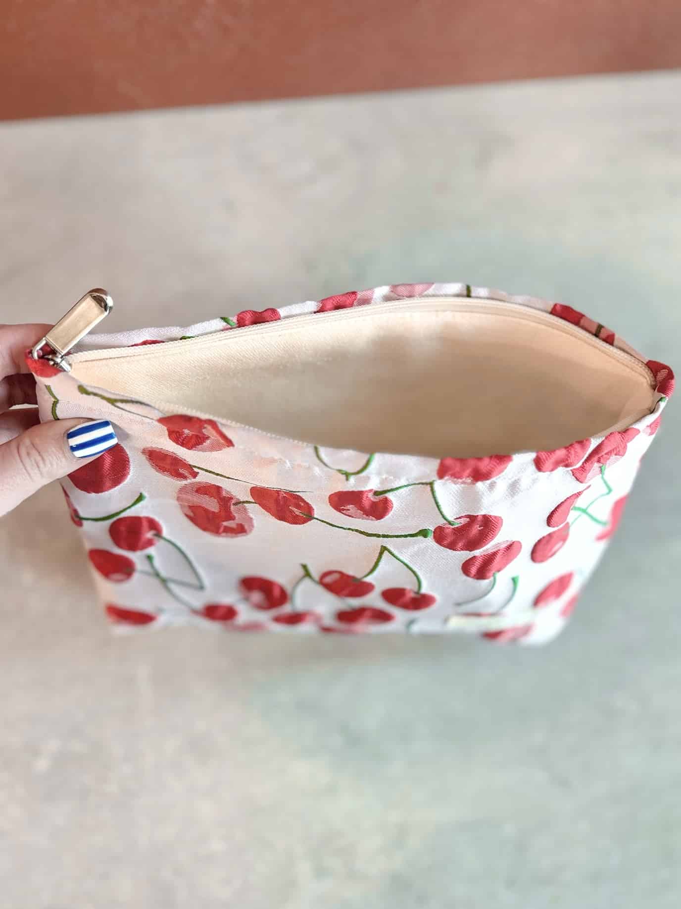 Top-down view of the Red Cherry Makeup Bag with zipper open, showing padded interior and beige cotton canvas lining.