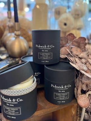 Group of Pickwick & Co. Leather Tobacco Woods candles stacked on a wooden display, featuring sleek black packaging and clean white wax.