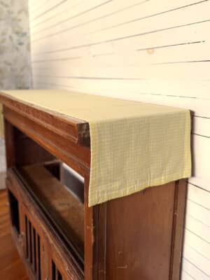 Yellow Gingham Table Runner Styled On Wooden Table