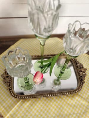 Tulip glass votive holders styled on a beaded gold mirror tray with a bright pink tulip.