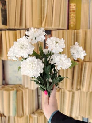 Hand holding a full bundle of White Scabiosa Sprays featuring lifelike white blooms for a lush floral display.