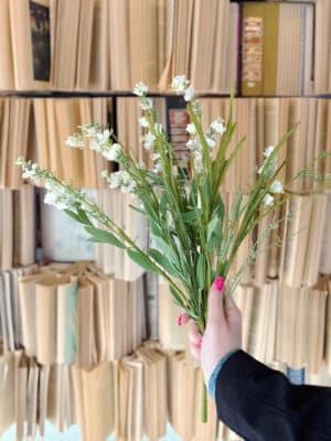 Cream Wild Flower & Grass Bush with wispy grass stems and neutral florals styled against a vintage book backdrop.