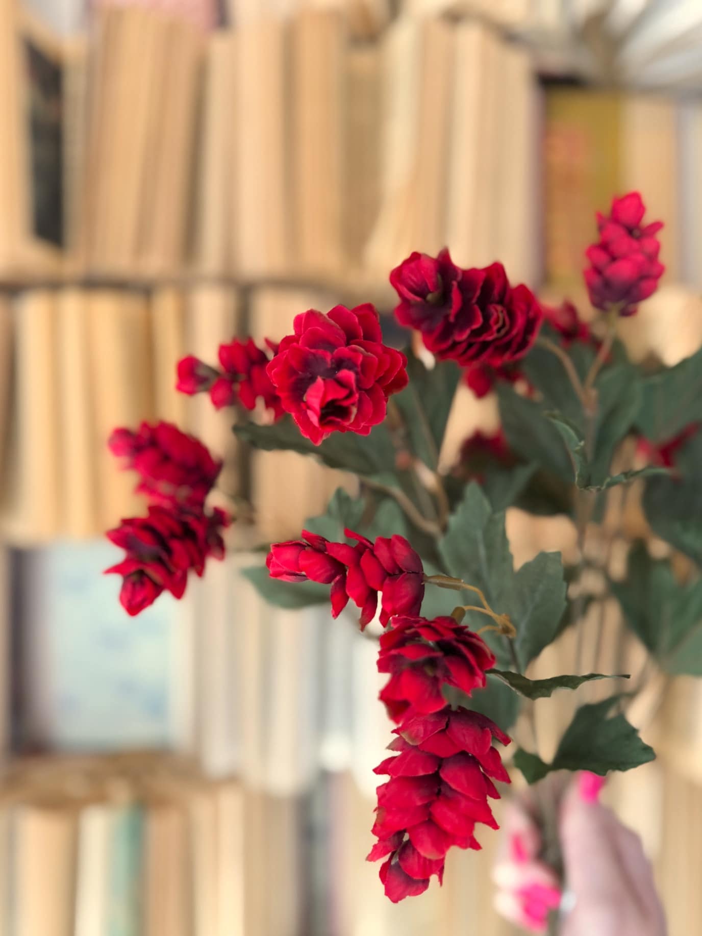 Close-up of lifelike red hops clusters with layered petals and soft green leaves.