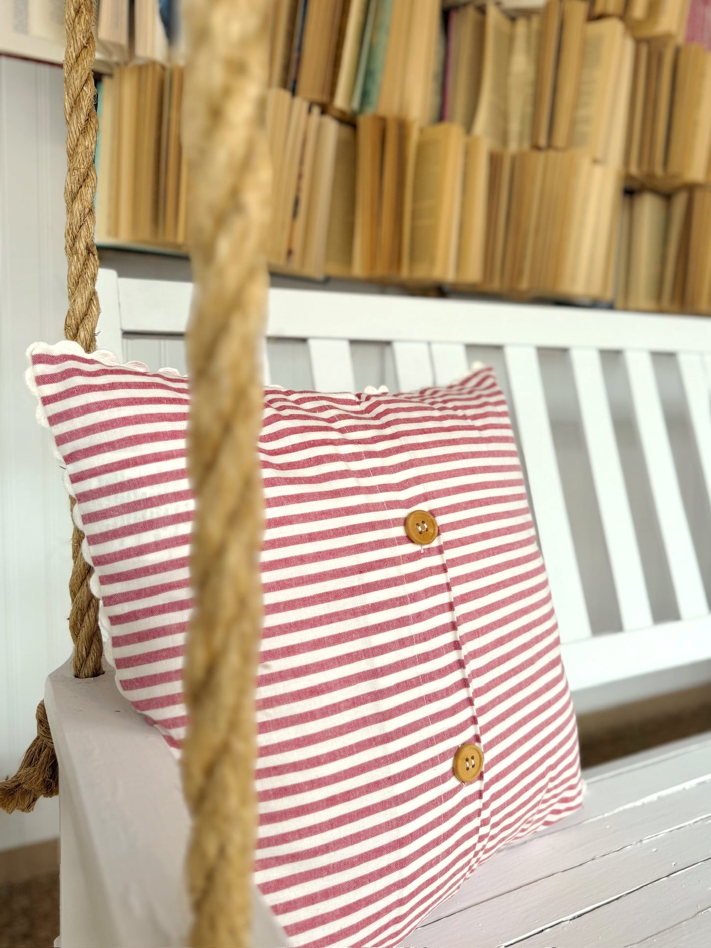 be-made-hays-ks-red-stripe-farmhouse-throw-pillow Farmhouse-style red stripe throw pillow with scallop edge detail, styled on a bench for cozy cottage decor.