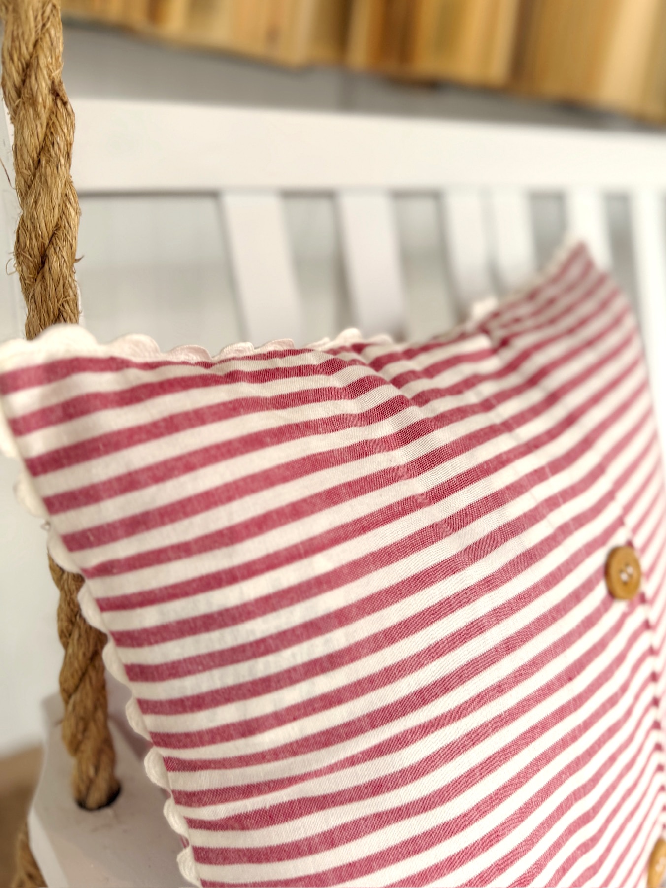 Cotton throw pillow with red ticking stripes and soft scalloped trim, adding vintage-inspired texture to a seating space.