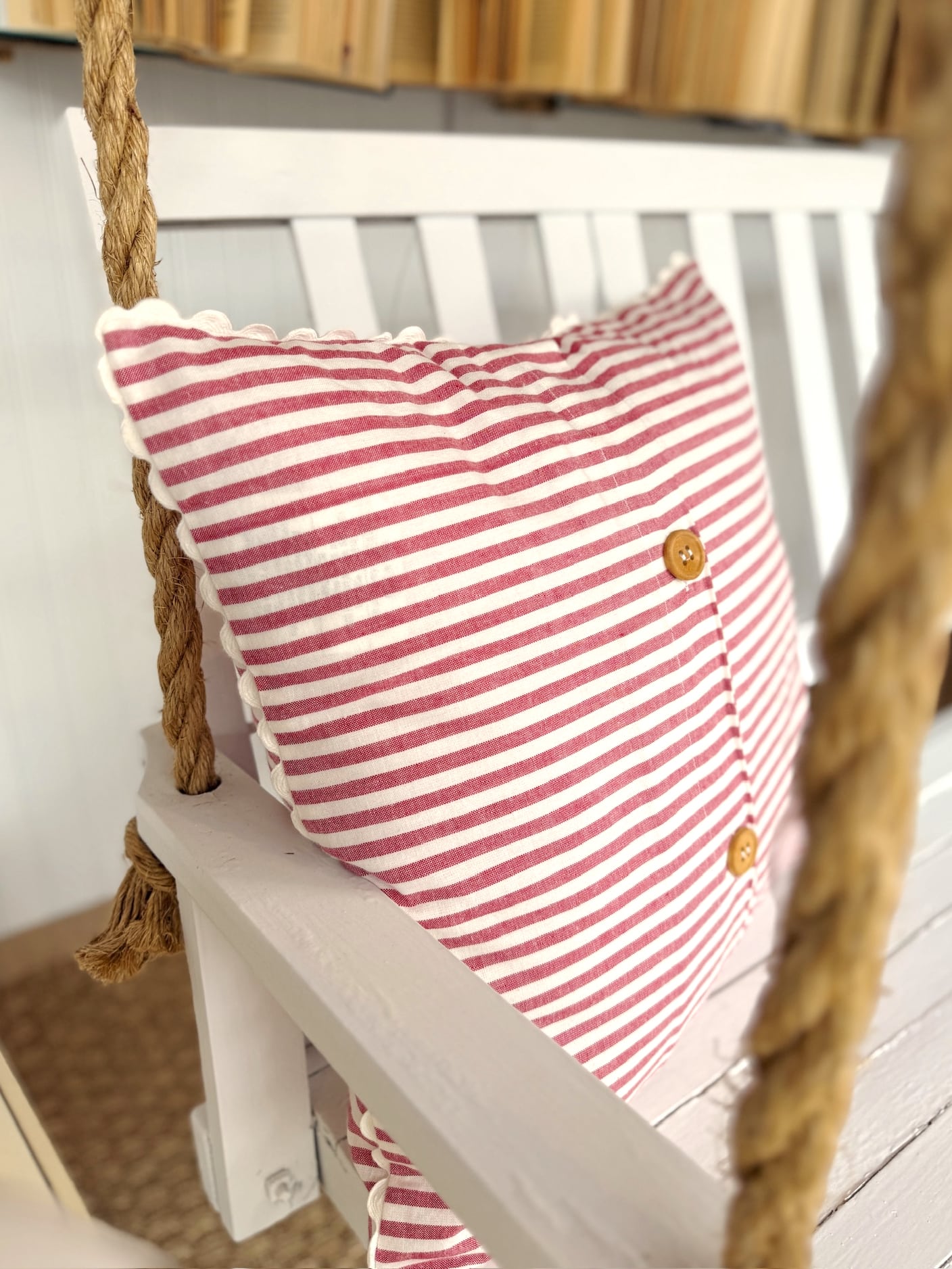 Red stripe scallop throw pillow made of cotton with classic ticking stripes and scalloped edges, styled on a white bench.