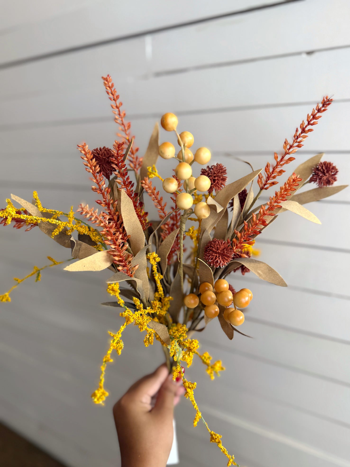 Mixed Fall Floral Pick held in front of a white plank wall, showing a full blend of color and texture