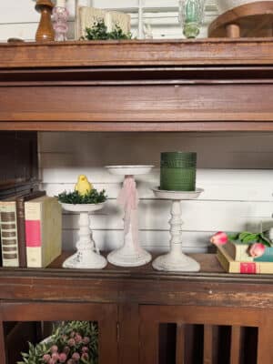 Distressed pillar candle holders styled on a decorative shelf.