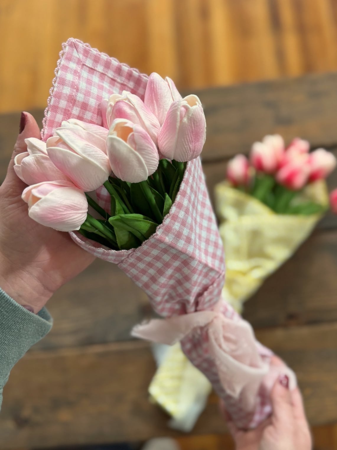 Close-up of light pink tulips wrapped in pink gingham fabric with a soft ribbon detail
