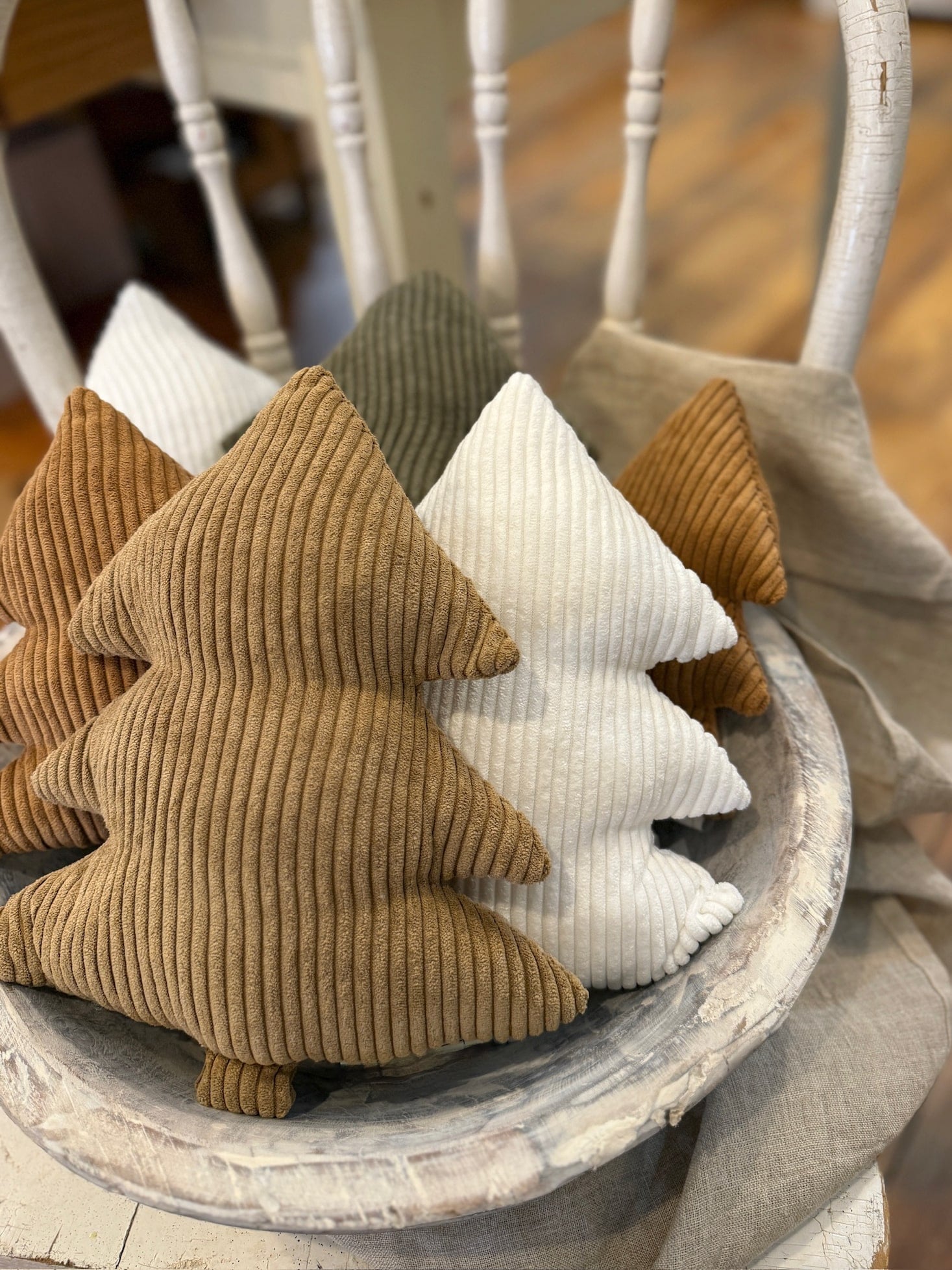 Set of ribbed corduroy stuffed trees in white, camel, cookie, and evergreen arranged in a rustic wooden bowl for a cozy holiday display.
