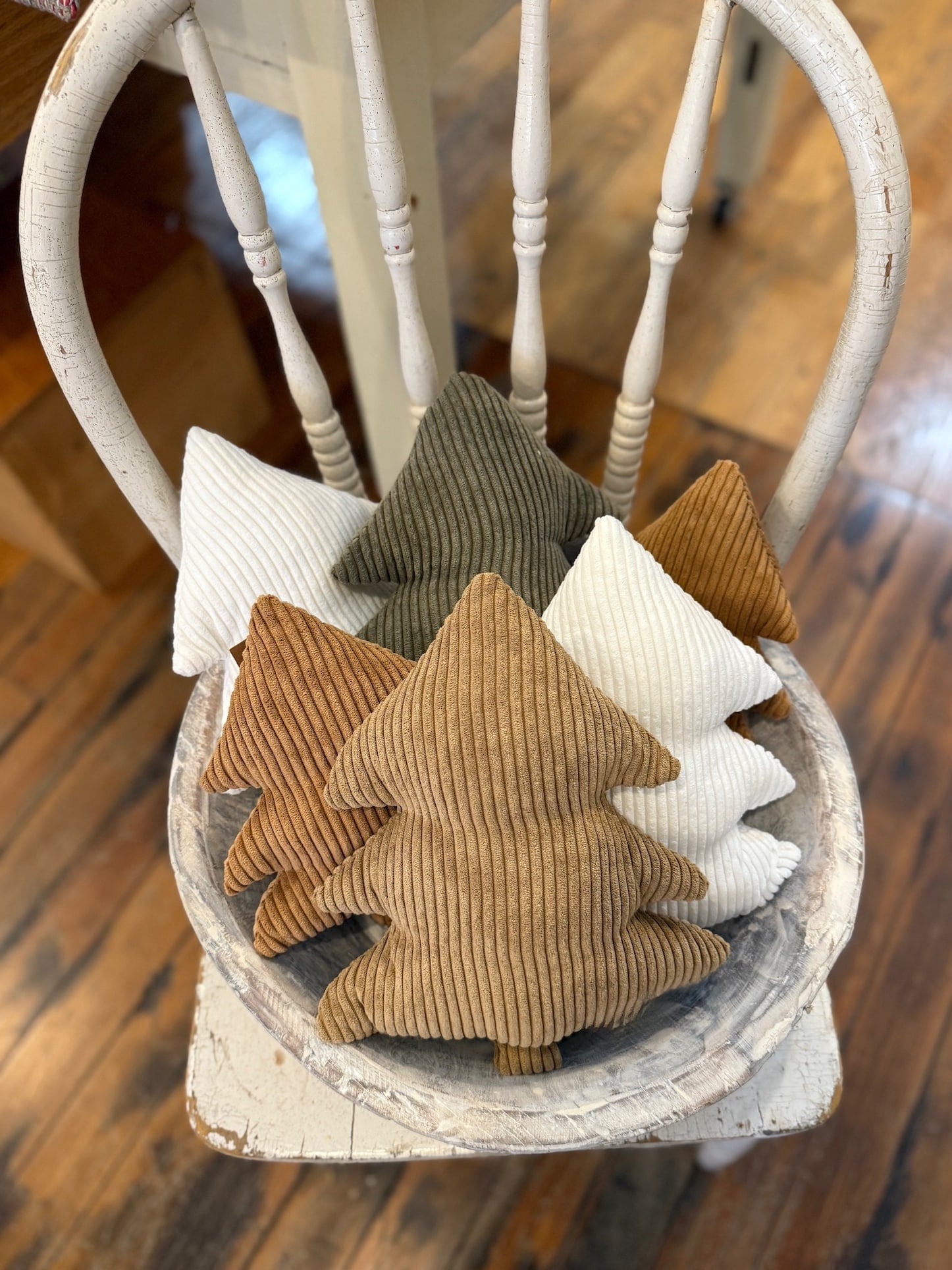 Corduroy Stuffed Tree Collection displayed on a white chair, featuring small and large trees in evergreen, camel, cookie, and white—perfect for cozy holiday décor.
