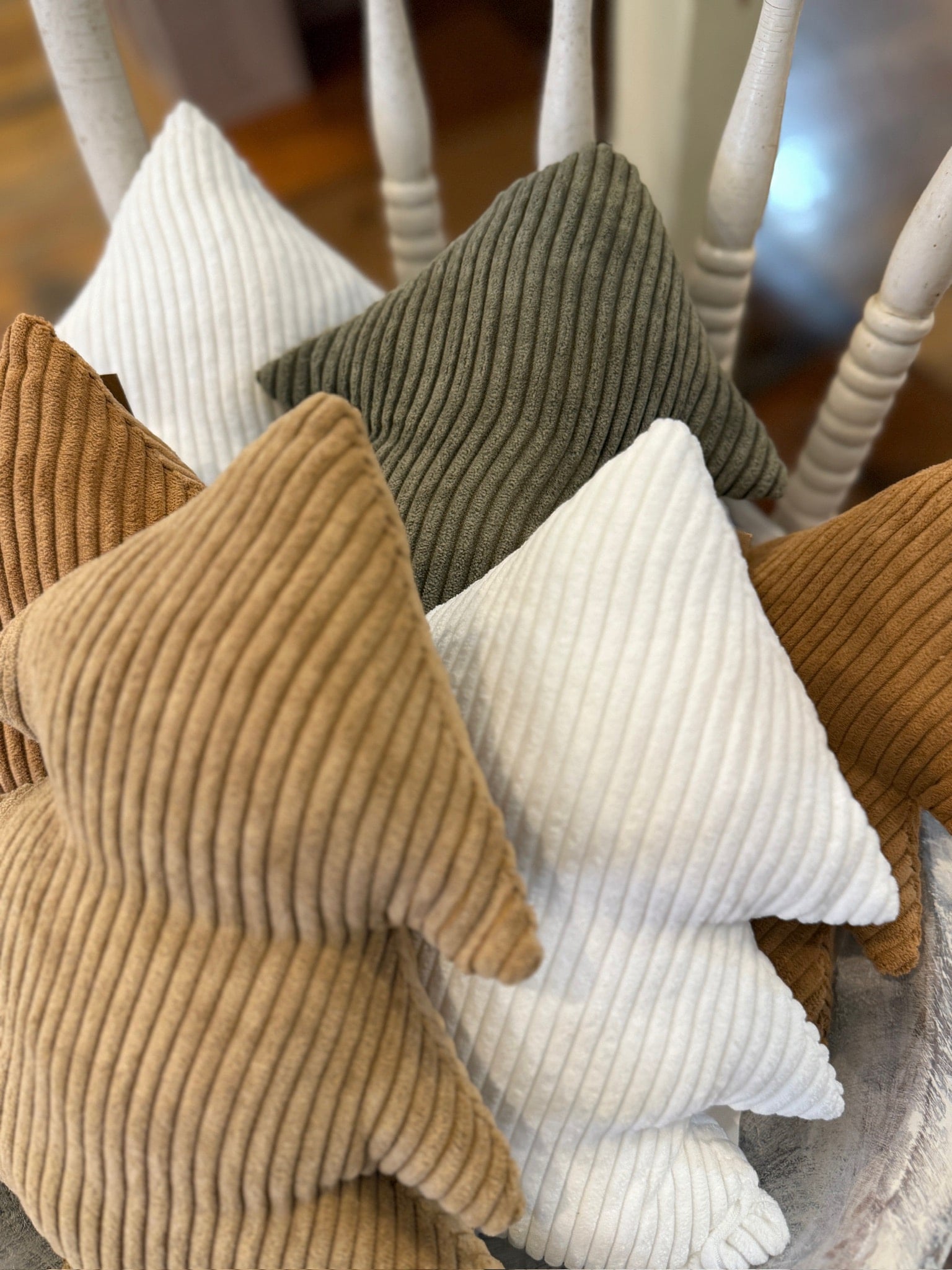 Assorted Corduroy Stuffed Trees in evergreen, camel, cookie, and white displayed together on a chair, showcasing soft ribbed textures and cozy neutral tones.