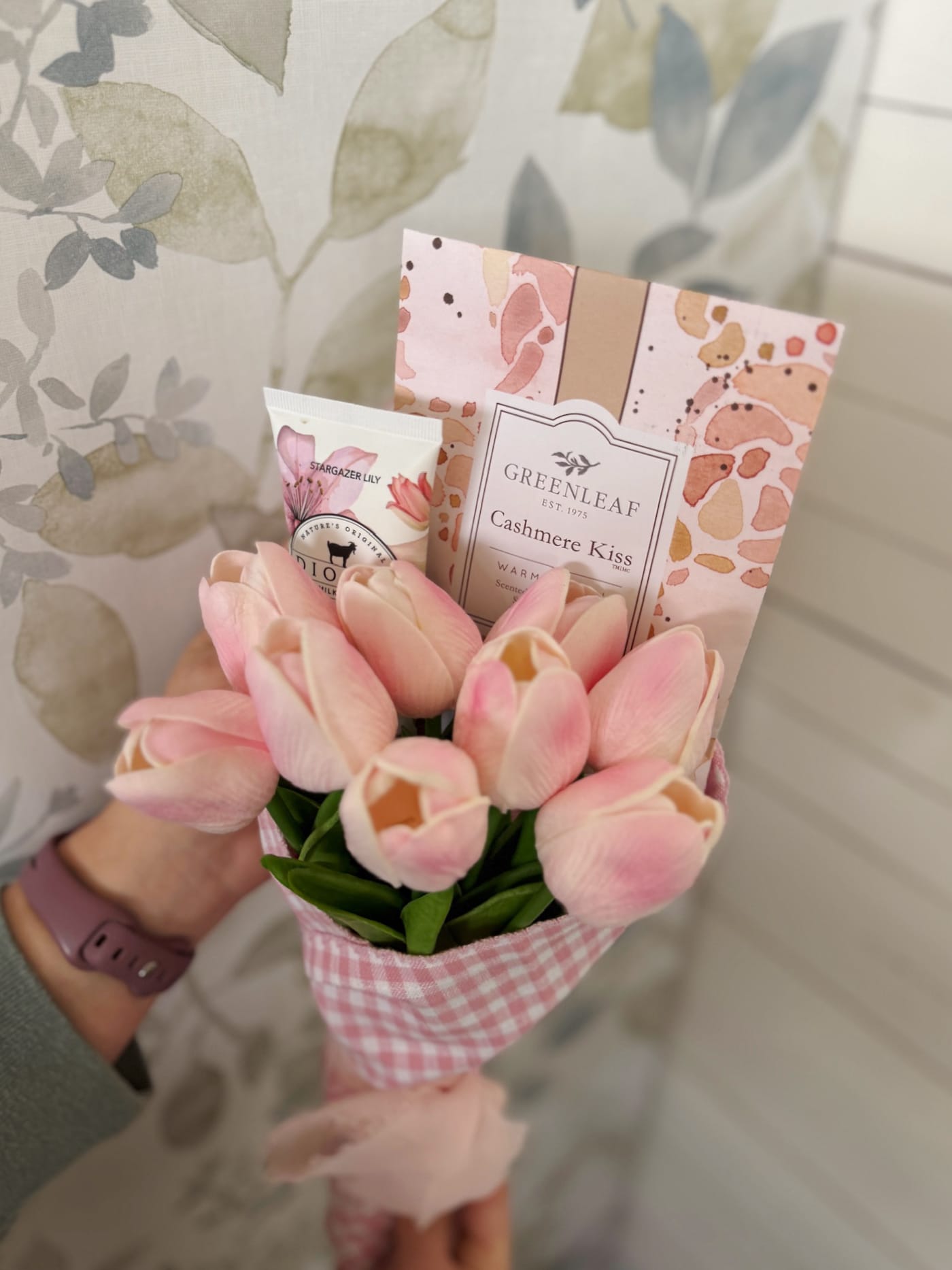 Light pink tulip bouquet wrapped in pink gingham with gift items tucked inside for a ready-to-gift floral bundle