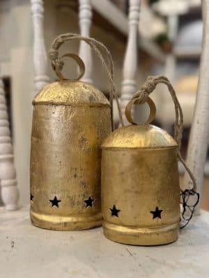 Hanging brass bells with star cutouts in a heavily distressed finish, styled for festive décor.