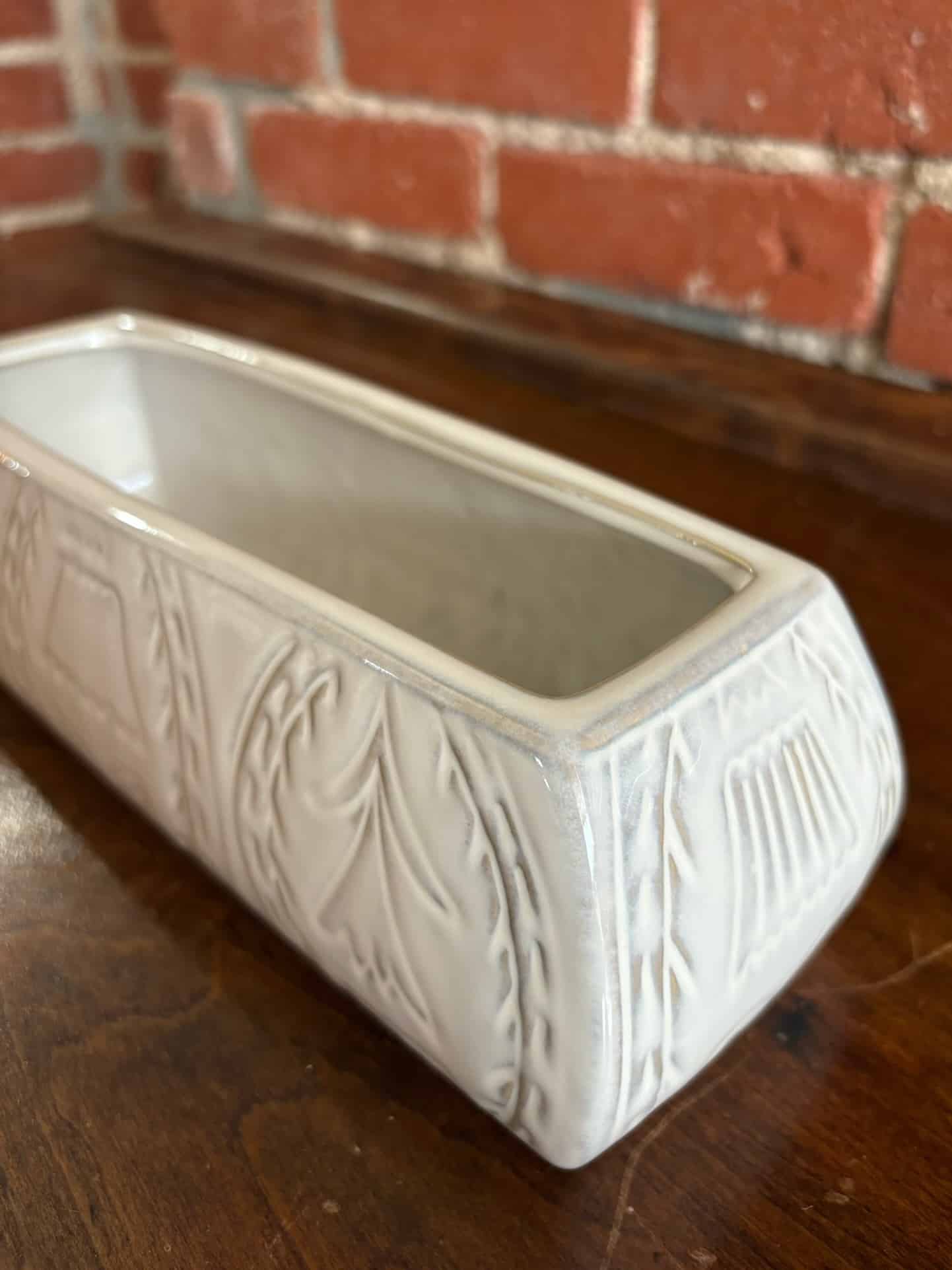 White debossed stoneware planter with floral design and reactive glaze finish, rectangular in shape.