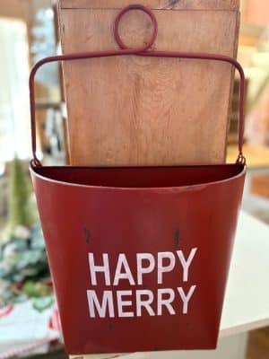 Red distressed holiday wall bucket with white “Happy Merry” lettering and a hanging handle.