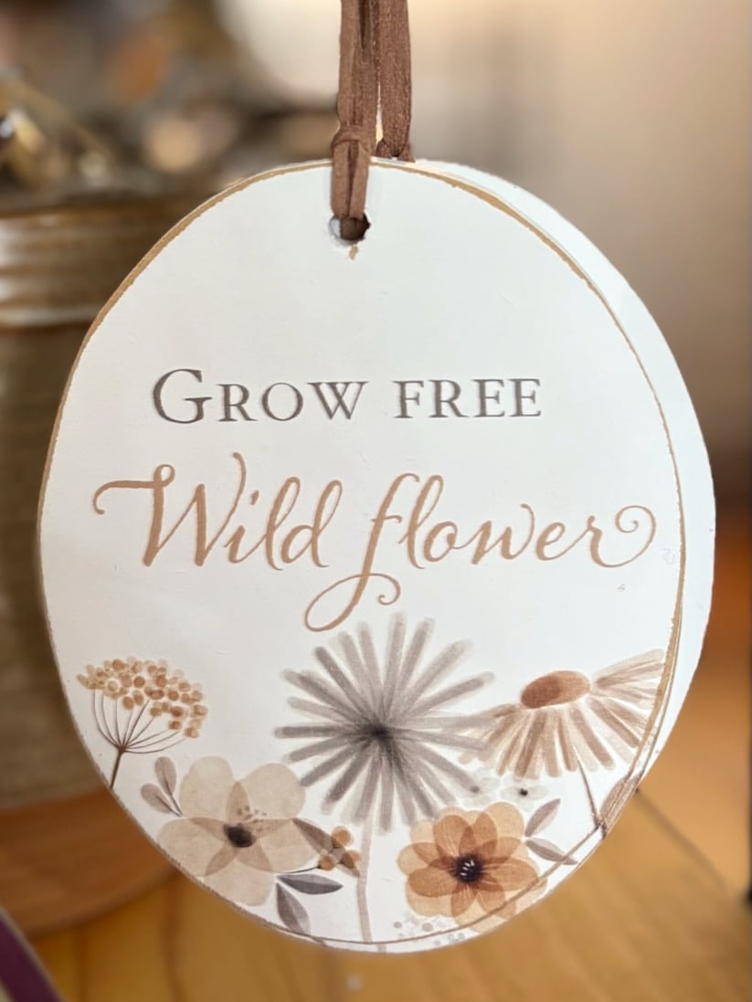 Wooden oval ornament featuring “Grow Free Wildflower” and delicate floral artwork.