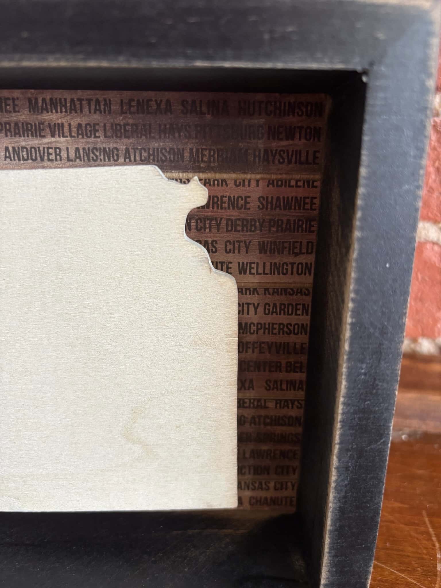 Rustic wooden Kansas sign with layered cutout and printed city names.