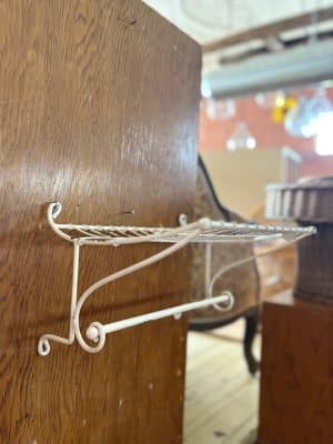 Vintage-inspired metal wall rack in distressed off-white with wire shelf and towel bar.